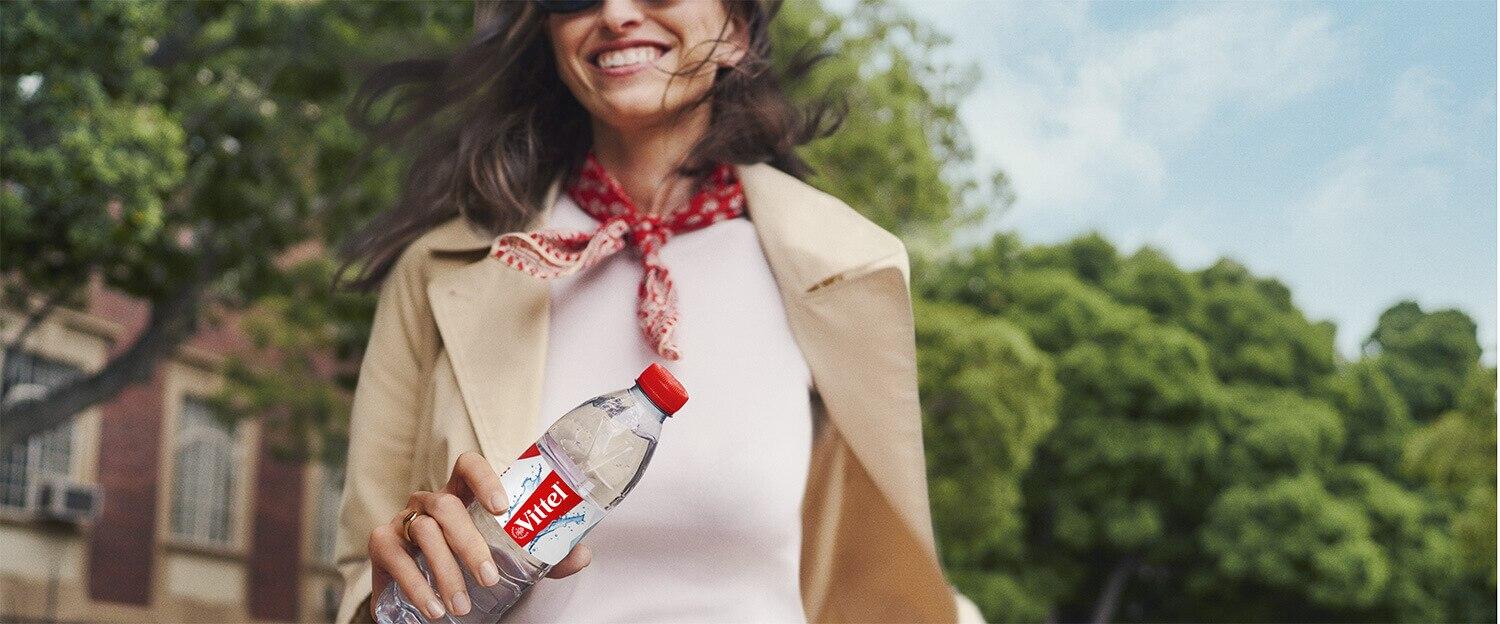 Personne tenant une bouteille d’eau Vittel lors d’une promenade en ville