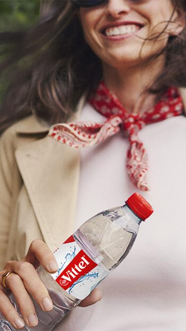 Personne tenant une bouteille d’eau Vittel lors d’une promenade en ville